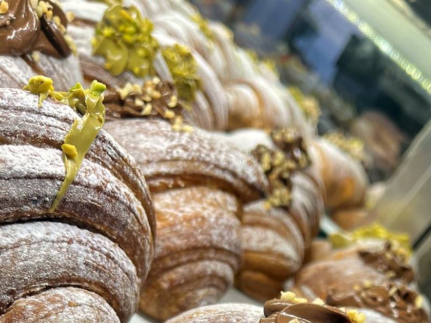 Sfogliatelle topped with pistachio cream and chopped pistachio, receding into the display